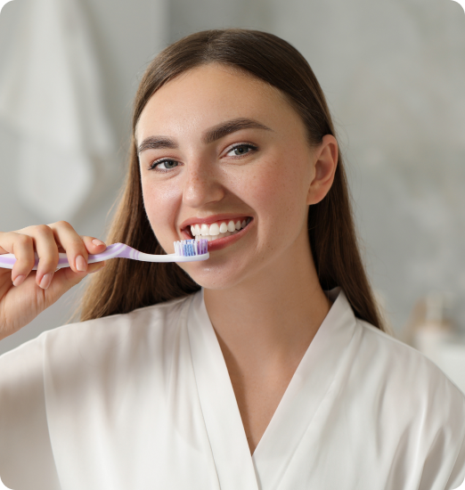 Woman smiling while brushing her teeth gently